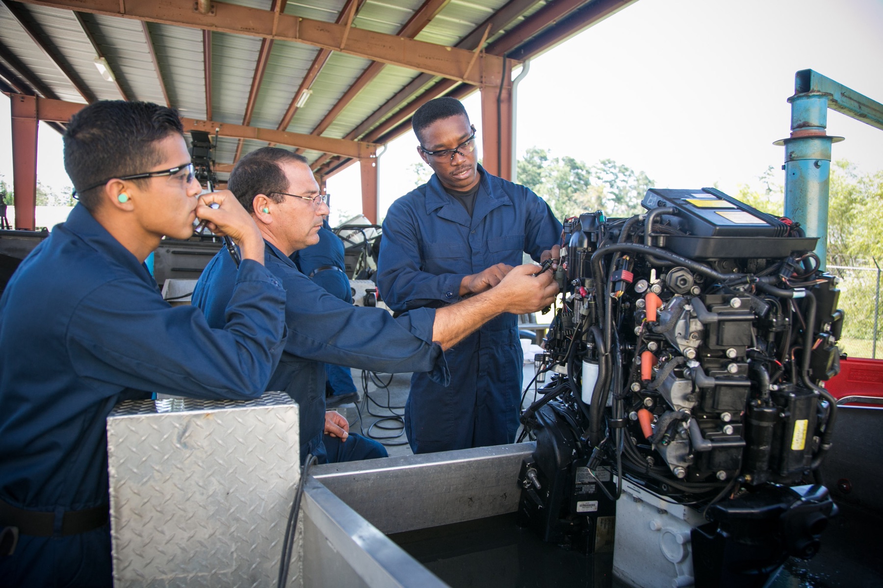 People working on an outboard motor